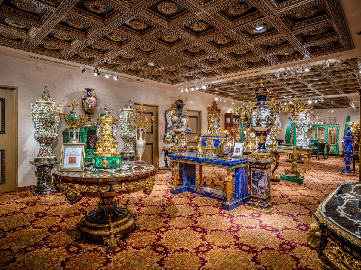 Empire Room at Régis Galerie LV — French antique vases, gilt-bronze clocks, Meissen porcelain, malachite cabinet, lapis console, coffered Greek-key ceiling.